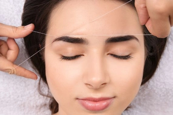 Professional eyebrow threading procedure on sensitive skin