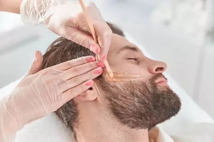 Man receiving professional eyebrow and facial hair grooming to enhance overall appearance and definition