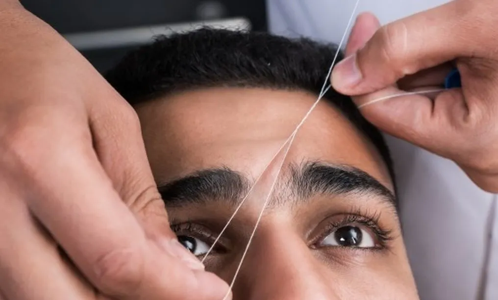 Close-up of gentle facial threading process on a male client with sensitive skin to prevent irritation