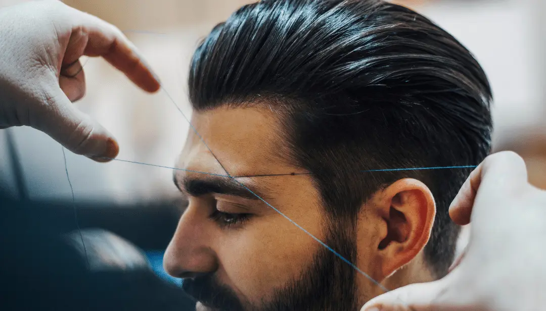 Professional technician performing full face and forehead threading for a male client at a Manhattan salon
